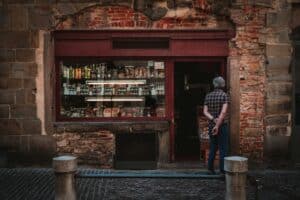 L'ingresso di una piccola bottega in un centro storico, con un cliente che sta entrando
