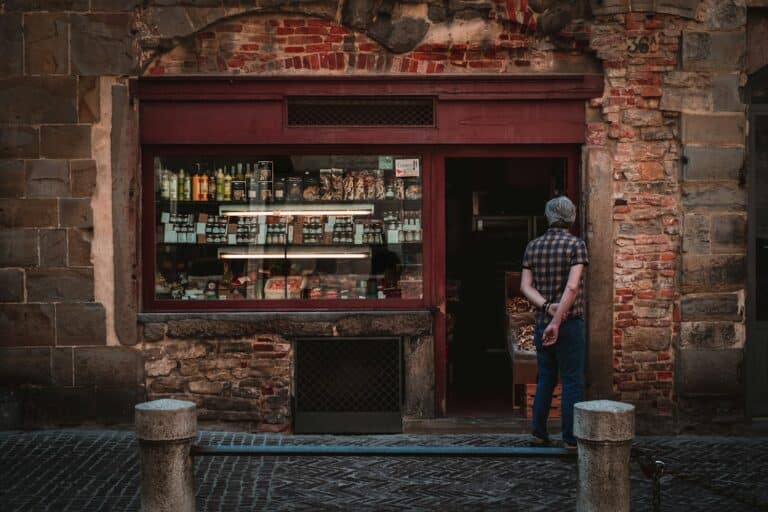 L'ingresso di una piccola bottega in un centro storico, con un cliente che sta entrando