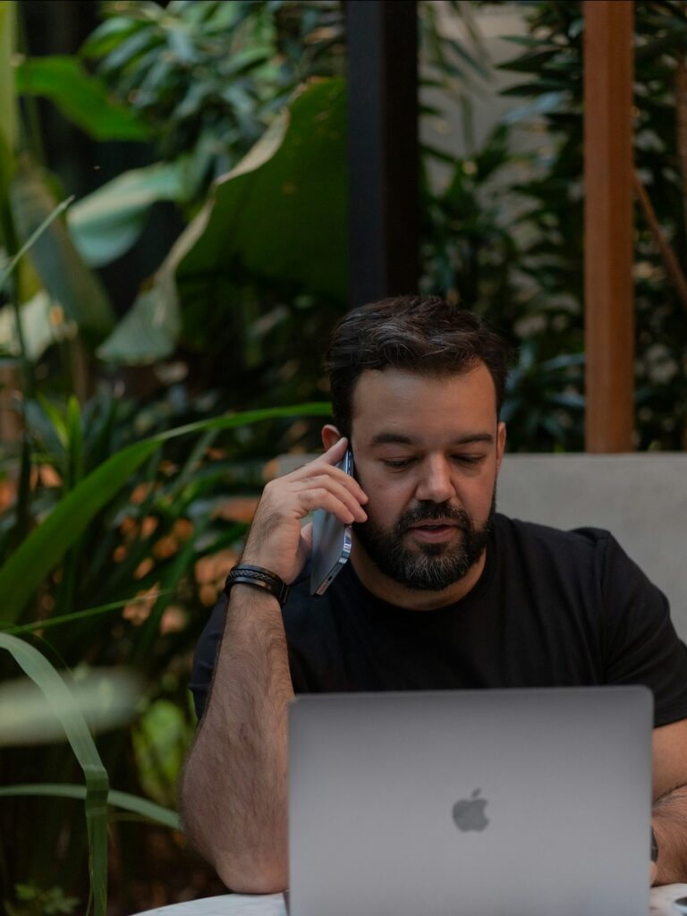 Titolare che richiama un cliente dal telefono con il CRM aperto sul portatile