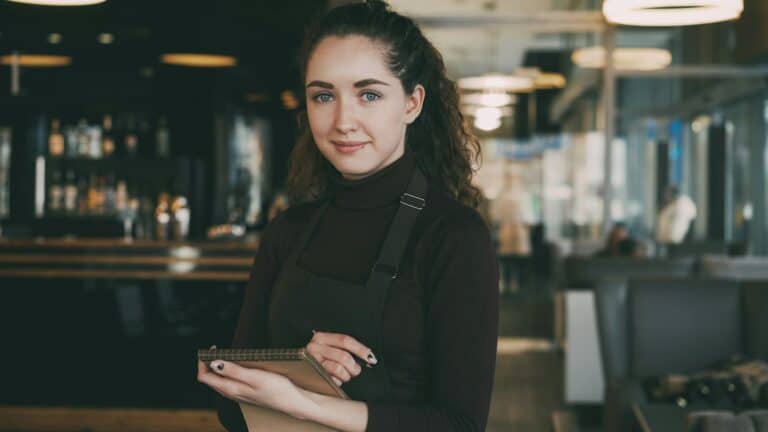 Titolare di un locale con il telefono in mano, pronta a controllare come compare la sua attività su Google