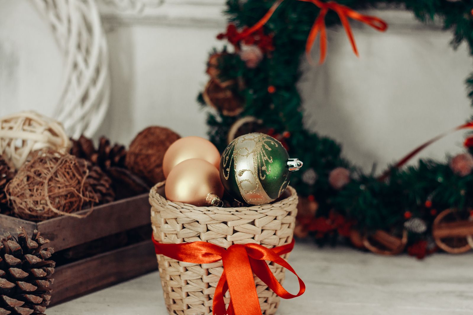 Cestino di vimini con fiocco rosso e palline di Natale su un tavolo, con una ghirlanda sullo sfondo