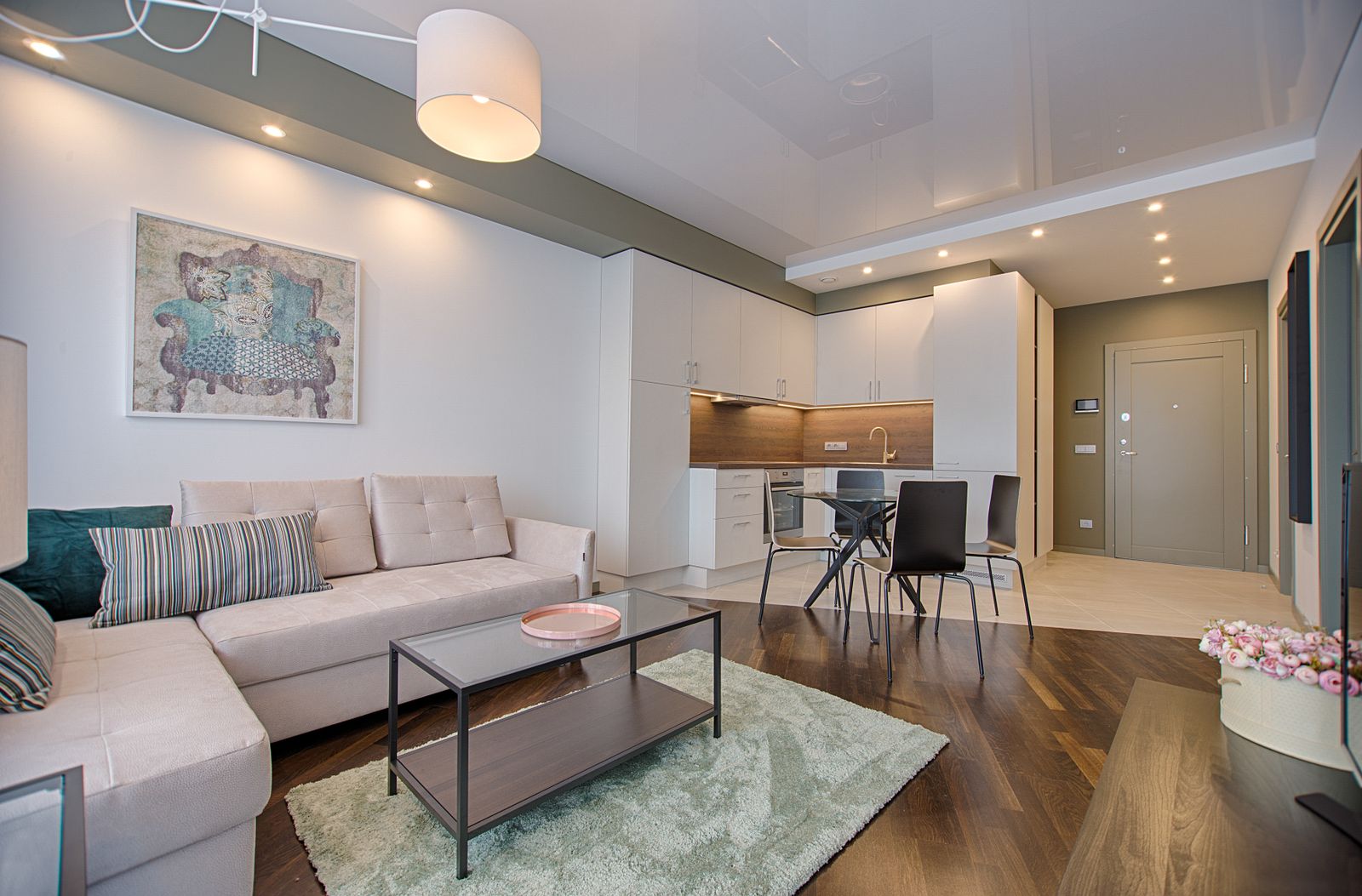 Soggiorno di un appartamento per vacanze con divano chiaro, tavolino e angolo cucina sullo sfondo