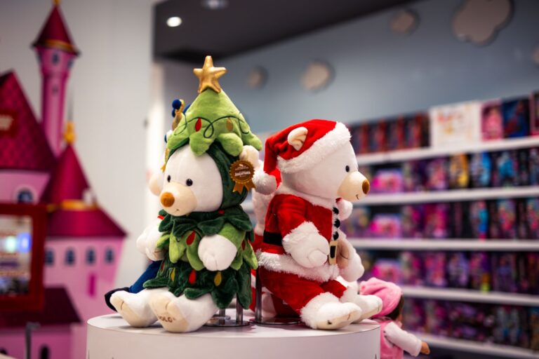 Peluche di orsetti vestiti da Babbo Natale e da albero di Natale esposti in un negozio di giocattoli