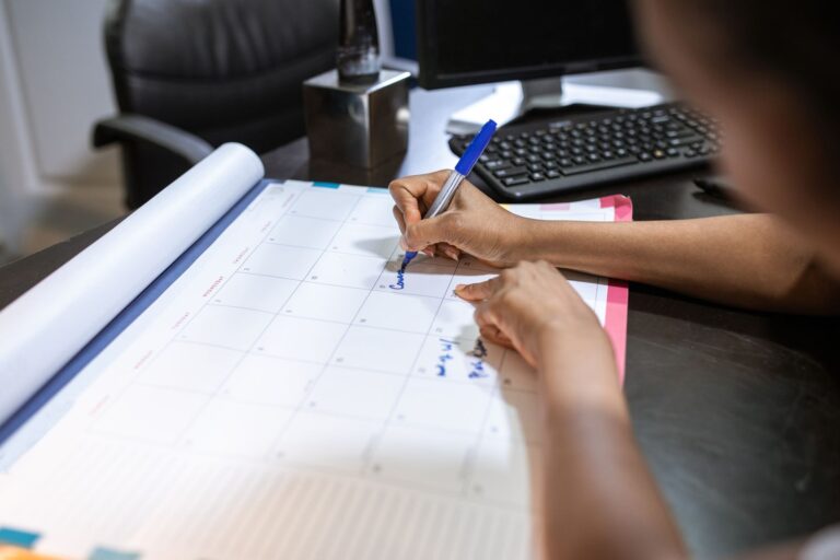 Una persona segna gli appuntamenti con il pennarello su un calendario mensile da scrivania