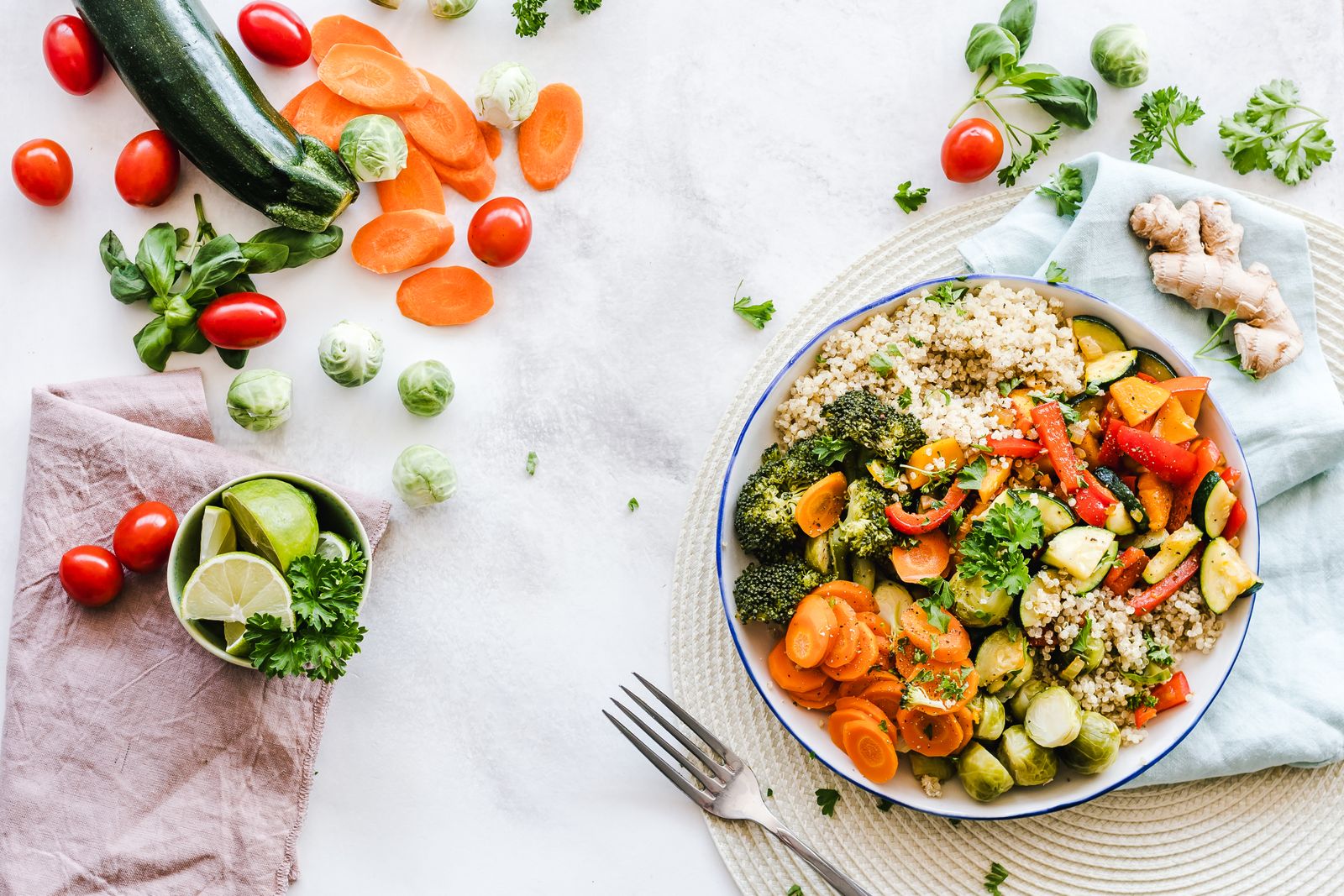 Piatto di quinoa con verdure al forno su un tavolo con pomodorini, carote e zucchine