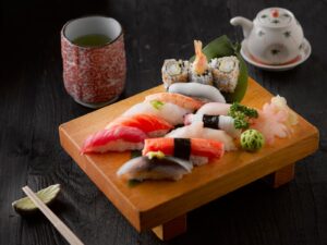 Nigiri e sushi misto su un tagliere di legno con tazza di tè verde e bacchette